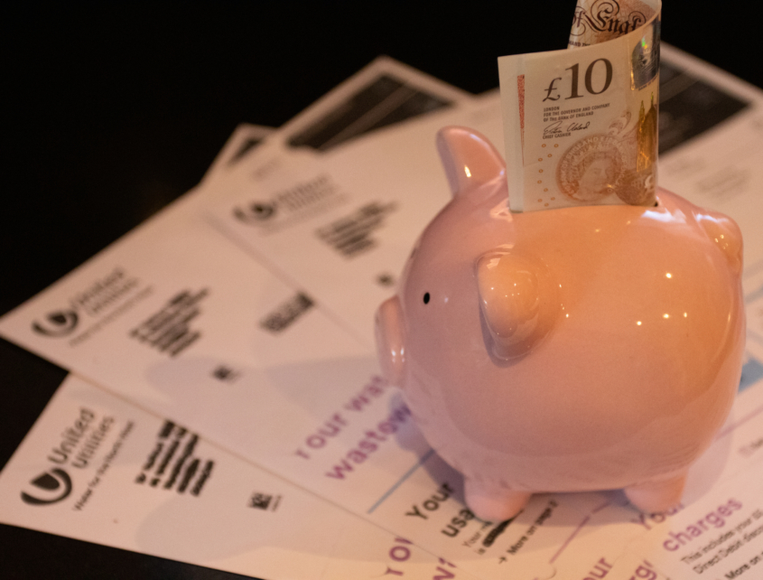 Piggy bank filled with money surrounded by utility bills