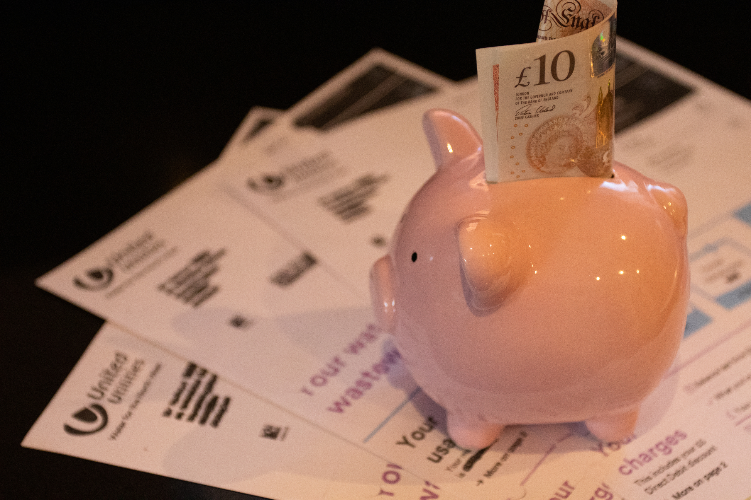 Piggy bank filled with money surrounded by utility bills