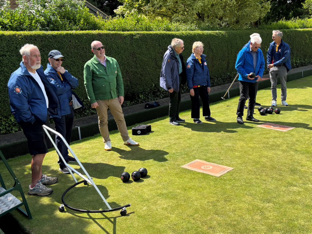 A group of people standing on a bowling green.