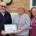 5 people standing outside a village hall holding a certificate