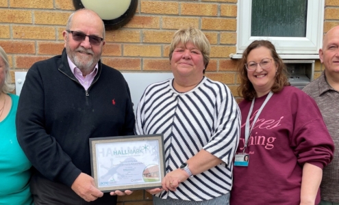 5 people standing outside a village hall holding a certificate