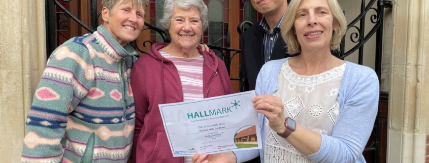 Four trustees standing outside a village hall holding a certificate