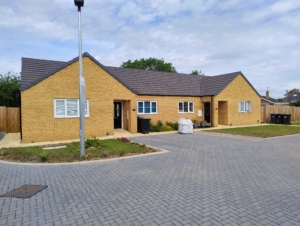 two semi detached bungalows with a yellow brick and a grey road